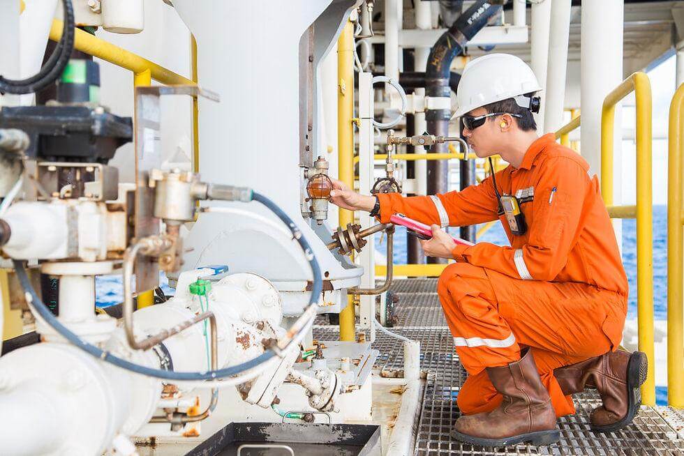 Offshore engineer in orange coveralls inspecting process equipment