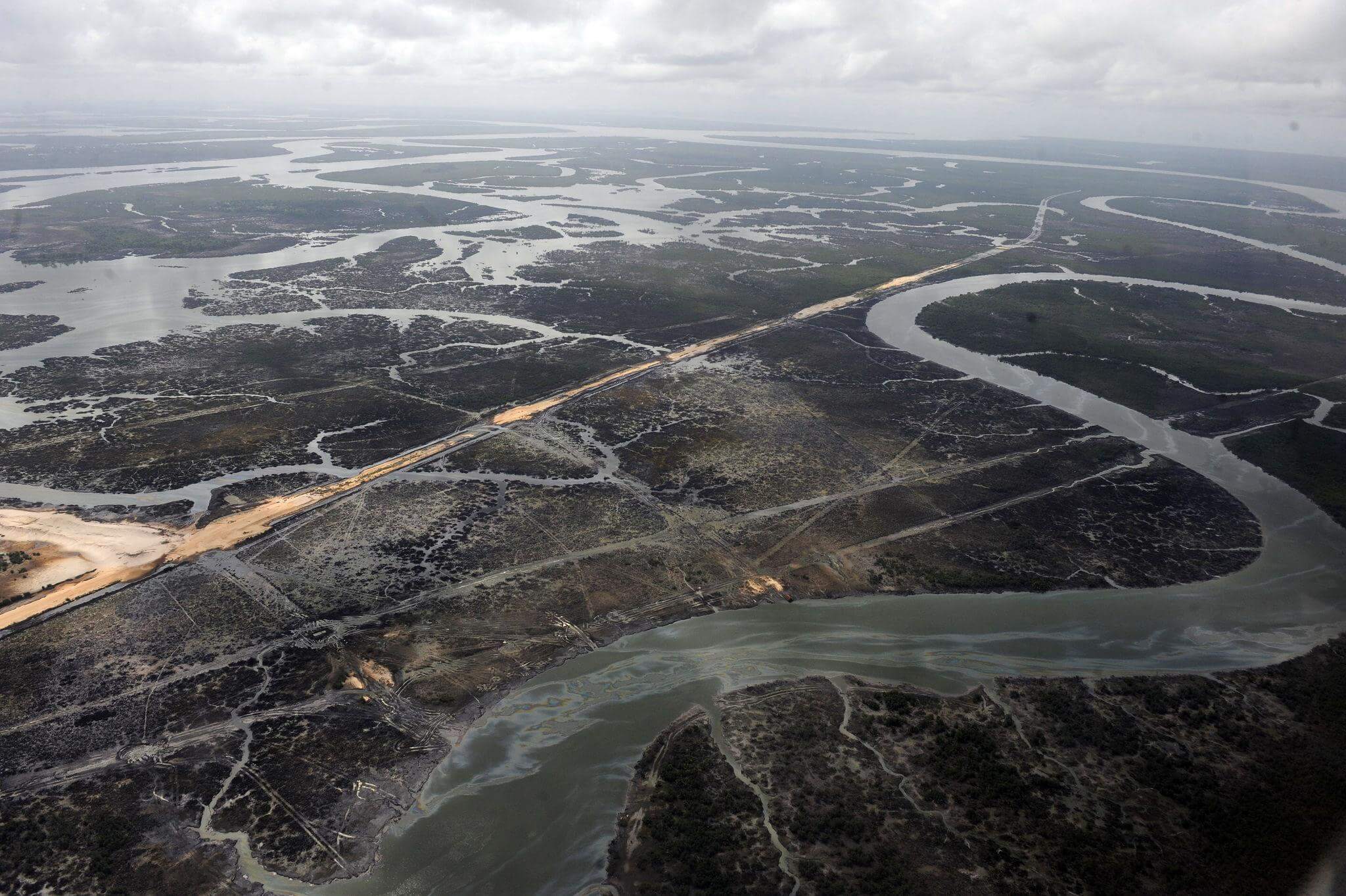 Aerial view of a winding creek and darkened, affected land in the Niger Delta