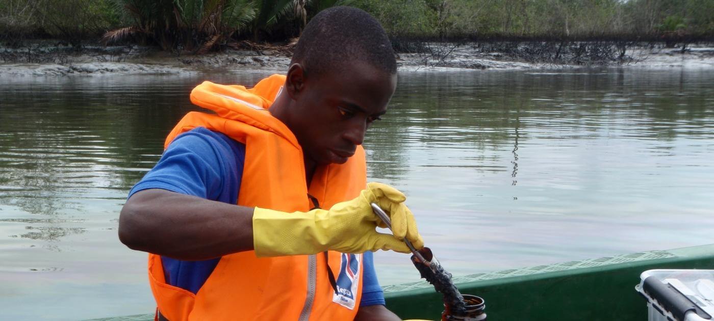 Field researcher collecting an environmental sample from a waterway